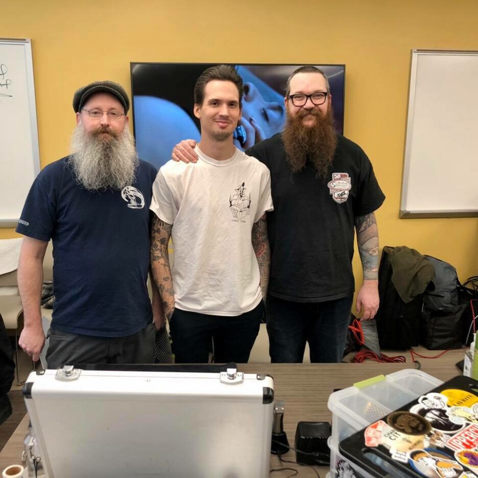 3 barbers standing next to each other about to cut hair at the shelter.